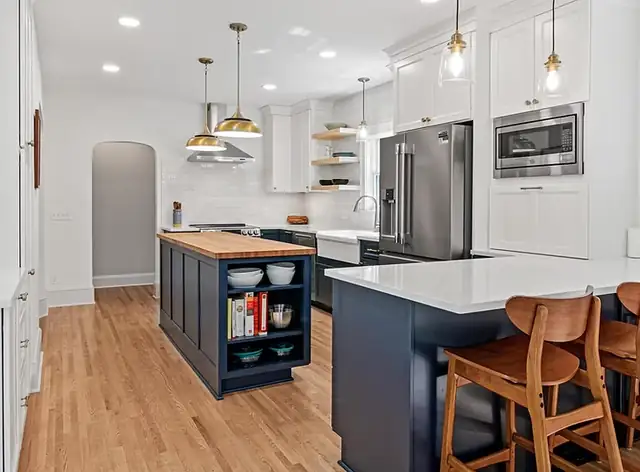 Executive Craftsman addition project in St. Paul with a new kitchen island and peninsula, white cabinets and brass pendants