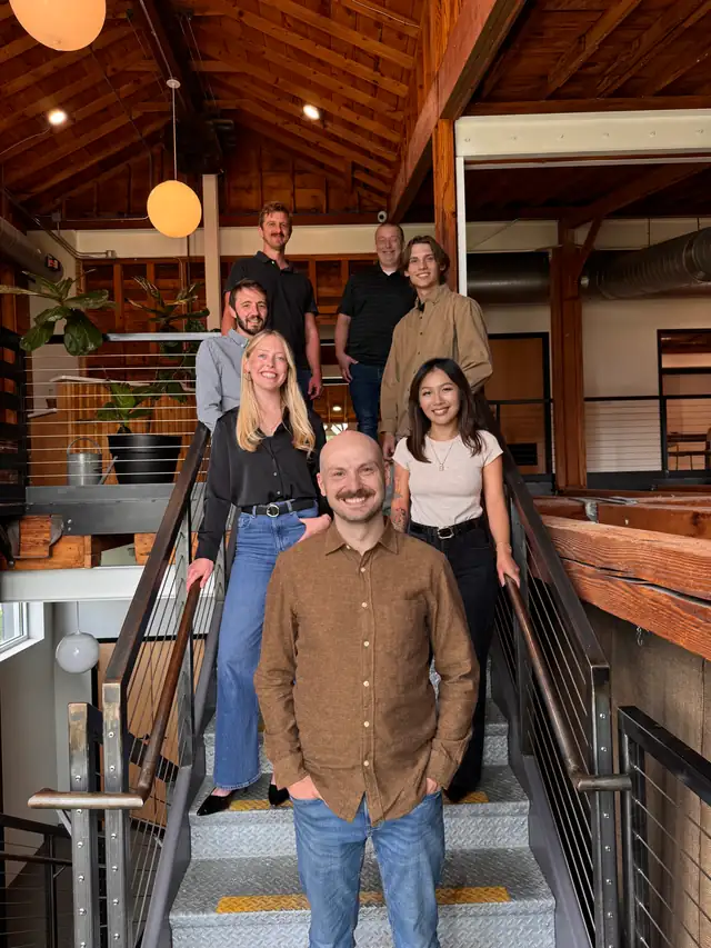 The Red Fox Remodeling team standing together on an open staircase under a wood-beamed ceiling