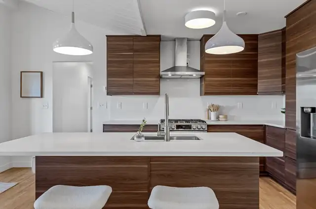 Golden Valley kitchen remodel with walnut slab cabinets, large white island and stainless range hood